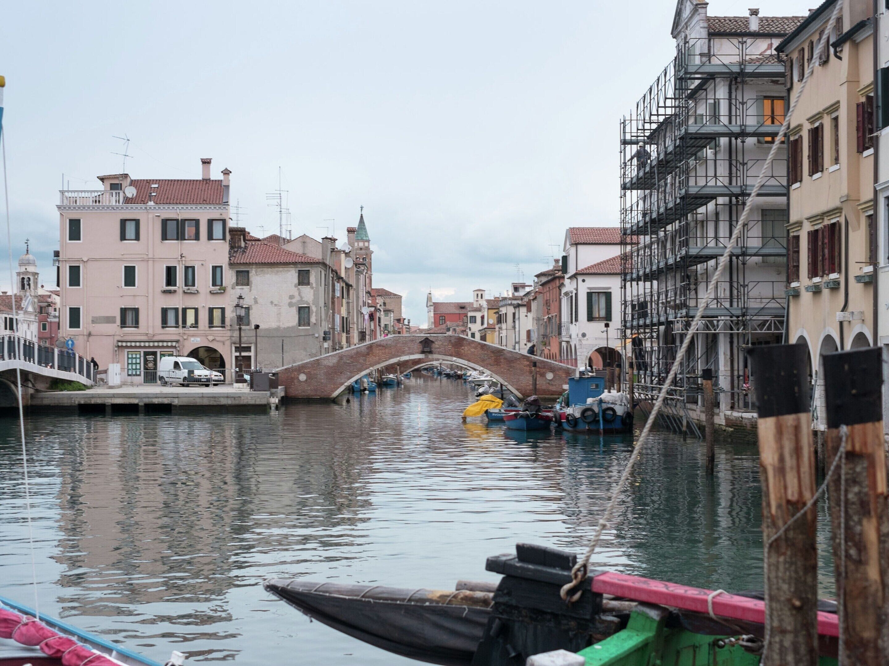 A canal with a bridge, boats, and buildings along the water.