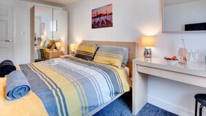 A hotel room with a bed, bedside table, lamp, and a painting on the wall. - Seasalt Twobedroom Apt in Skinningrove (Saltburn-by-the-Sea)