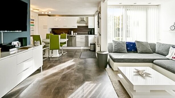 A modern living room with a sofa, coffee table, and a flat-screen TV. - Huijsmans Verhuur Type A de Luxe Grevelingen 29 (Ouddorp)