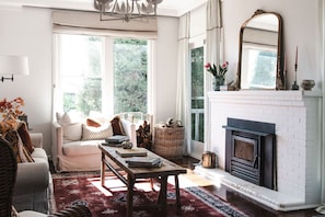 Una sala de estar acogedora con chimenea, un sofá, una mesa de centro y un ventanal grande.