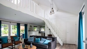 A spacious living room with a dark leather sofa, a round coffee table, and a staircase leading to an upper level. - Holiday Home With Covered Terrace in Rhenen (Rhenen)