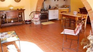 A cozy living room with a fireplace, a dining area, and a kitchen with an archway. - Spacious Tuscan Villa Retreat (Palaia)