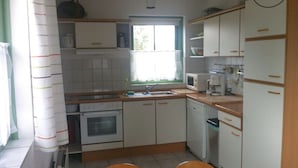 Pieni, käytännöllinen keittiö, jossa on valkoiset kaapit, mikroaaltouuni, kahvinkeitin ja pesuallas.