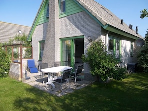 A two-story house with a patio area featuring a table and chairs. - Beach Pearl Julianadorp (Julianadorp)
