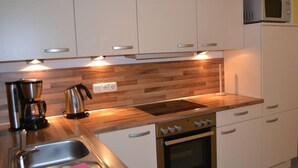 A modern kitchen with wooden countertops, stainless steel appliances, and white cabinetry. - Beach Dune 18 on the Beach (Karlshagen)