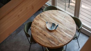 A round wooden table with a decorative bowl in the center, surrounded by four green chairs. - Nice Apartment on Ameland With Balcony/terrace (Buren)