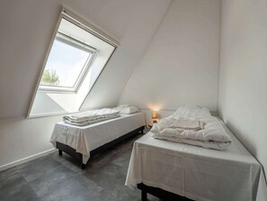 A small, well-lit attic bedroom with two beds, a skylight, and a nightstand with a lamp. - Nice Apartment on Ameland With Balcony/terrace (Buren)