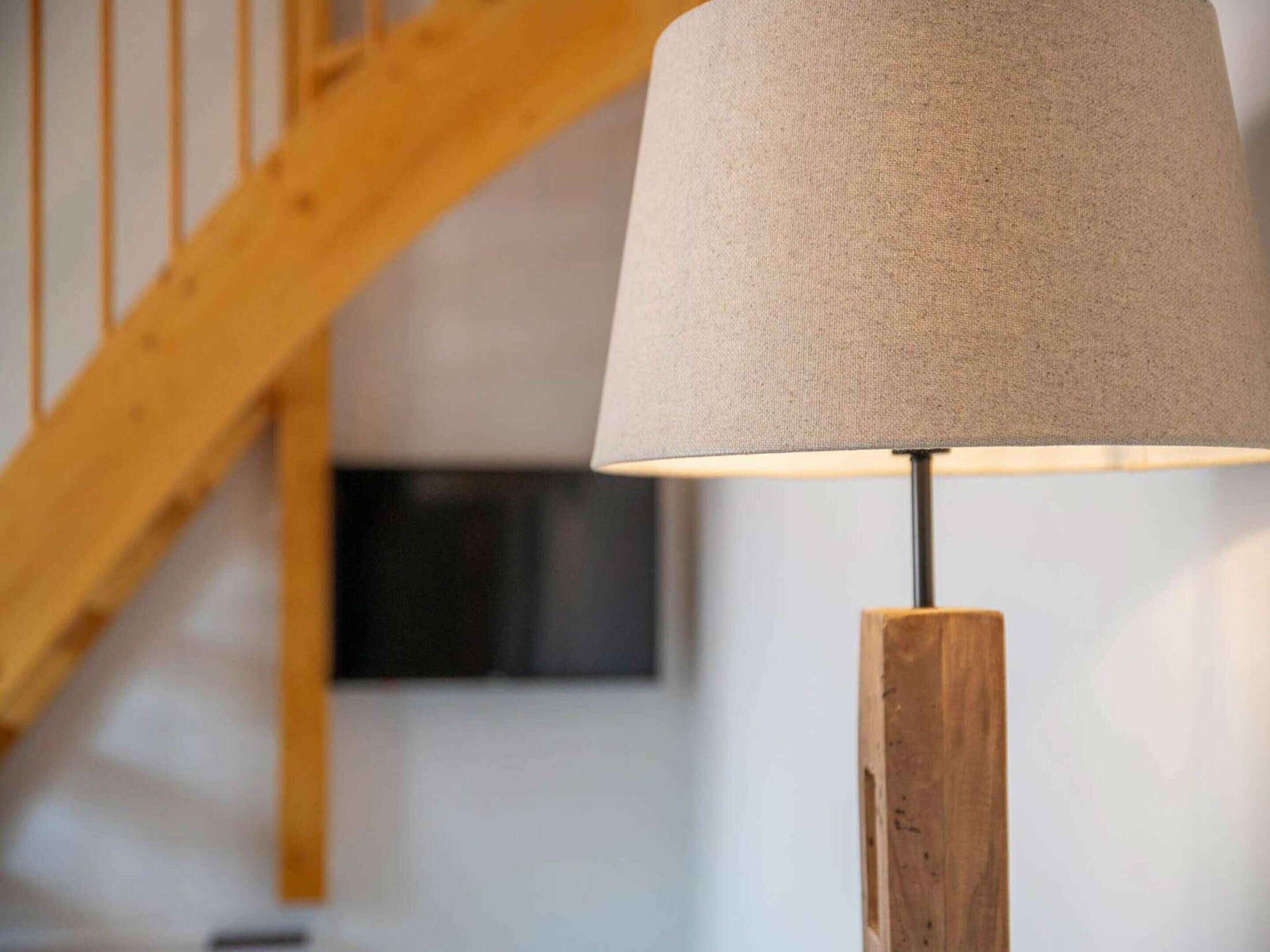 A lamp with a wooden base and a beige lampshade.