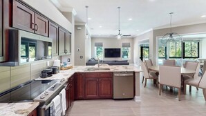 A modern kitchen with a central island, built-in appliances, and a dining area with a view.