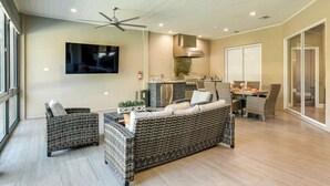 A spacious living area with a large sofa, two armchairs, a dining table, and a kitchen area with a grill. - Private Oasis: Heated Pool & Spa (Riverview)