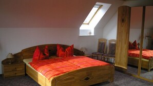 A bedroom with a wooden bed, a nightstand, a dresser, a mirror, and a skylight. - Sachon Comfortable Holiday Residence (Nebelschütz)