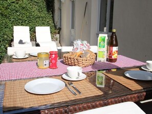 Una mesa de desayuno dispuesta con platos, tazas, cubiertos y diferentes alimentos.
