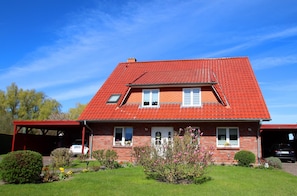 A two-story house with a red-tiled roof, a covered porch, and a garage. - Familienfreundliche Haushaelfte in Alt Bukow (Alt Bukow)