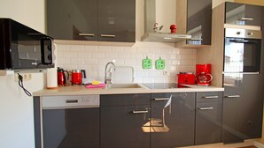 Een moderne keuken met donkere kastjes, een magnetron, een koffiezetapparaat en een vaatwasser.