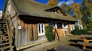 A rustic wooden building with a thatched roof, a wooden staircase, and a picnic table area. - Dreamtime Modern Retreat (Zinnowitz)