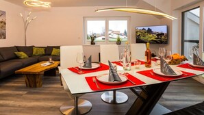 A modern dining area with a white table set for four, red placemats, and a bottle of wine. - Dreamtime Modern Retreat (Zinnowitz)