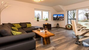 A modern living room with a sofa, coffee table, and a TV. - Dreamtime Modern Retreat (Zinnowitz)