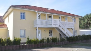 A two-story building with a red-tiled roof, a balcony with white railings, and a staircase leading to the upper floor. - Beach Dune 12 on the Beach (Karlshagen)