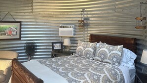 A rustic room with a wooden bed, a ceiling fan, a wall-mounted air conditioner, and a framed picture. - Best Mountain View in Utah. Rustic ranch setting.  (Provo)
