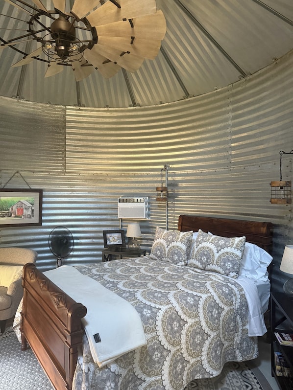 A rustic room with a wooden bed, a ceiling fan, a wall-mounted air conditioner, and a framed picture. - Best Mountain View in Utah. Rustic ranch setting. (Provo)