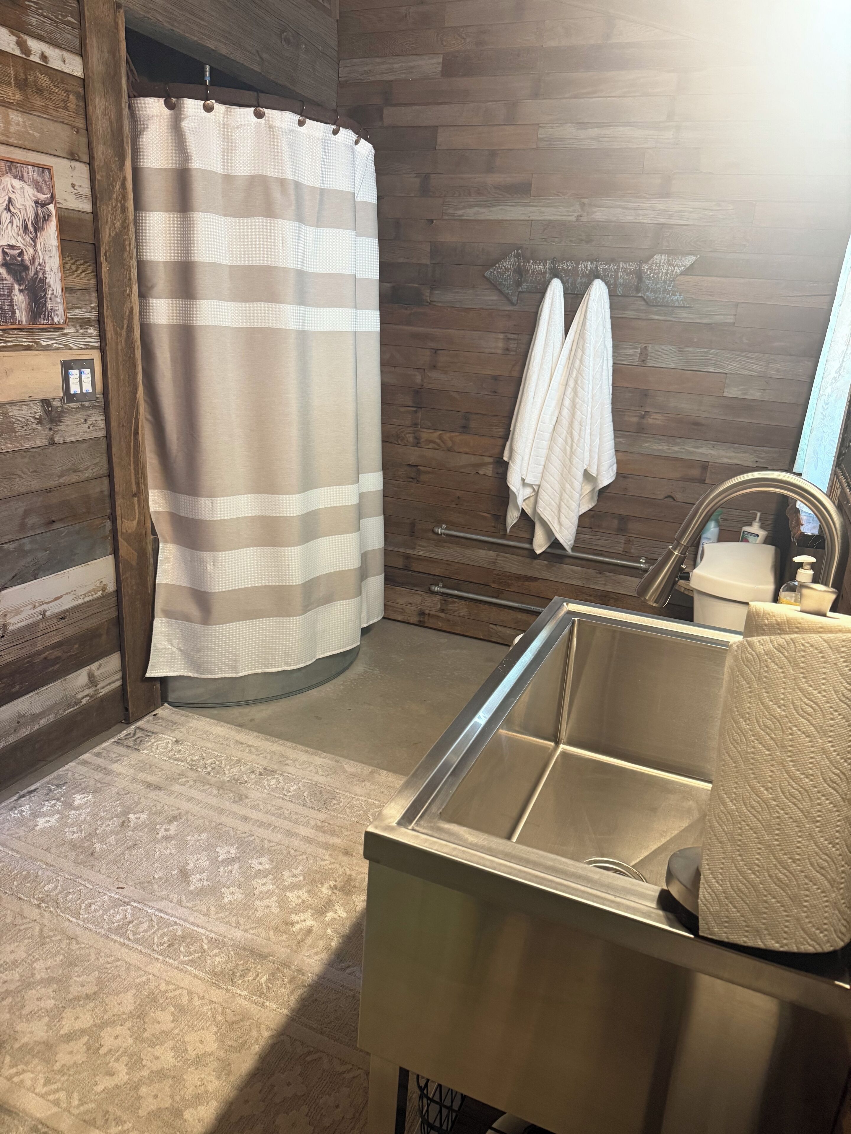 A bathroom with a shower curtain, a sink with a towel, and wooden walls.