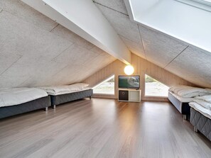 A bedroom with a sloped ceiling, two beds, a television, and a large window. - 5 Star Holiday Home in Norre Nebel (Norre Nebel)