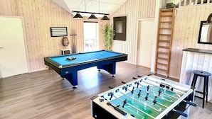 A room with a pool table, a foosball table, wooden walls, and a ladder. - 5 Star Holiday Home in Norre Nebel (Norre Nebel)