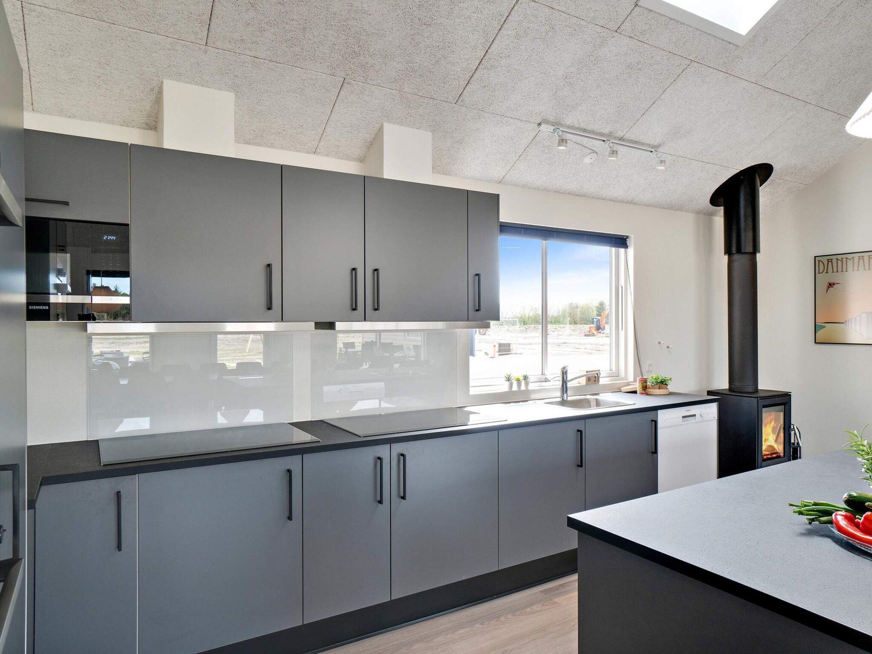 A modern kitchen with grey cabinets, a black stove, and a window with a view of the outside.