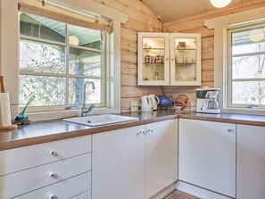 A kitchen with a sink, cabinets, and a window with a view of trees. - 6 Person Holiday Home in Ronne (Ronne)