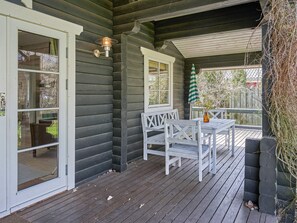 A wooden deck with a white table and chairs, a hanging light fixture, and a view of the outdoors. - 6 Person Holiday Home in Ronne (Ronne)
