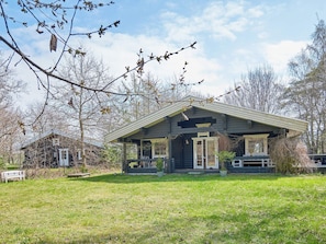 A rustic cabin with a porch, surrounded by a grassy yard and leafless trees. - 6 Person Holiday Home in Ronne (Ronne)