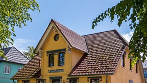 A yellow building with a tiled roof, a sign reading "Haus Ostscenize," and a white picket fence. - Holiday Apartment in Otseebad Wustrow (Ostseebad Wustrow)