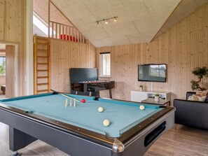 A pool table with balls, a foosball table, a TV, and a staircase.