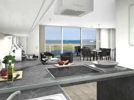 Una cocina moderna con isla, comedor y vista al mar.