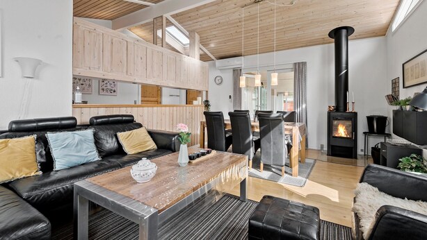 A modern living room with a fireplace, leather furniture, and a wooden ceiling. - 2 bedroom beautiful home in Esbjerg V (Esbjerg V)