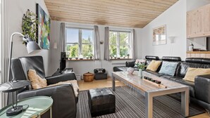 A modern living room with a wooden ceiling, leather sofas, a coffee table, and large windows with curtains. - 2 bedroom beautiful home in Esbjerg V (Esbjerg V)