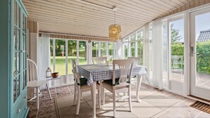 A conservatory with a table set for four, white chairs, and a hanging light fixture. - 2 bedroom beautiful home in Esbjerg V (Esbjerg V)