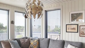 A modern living room with a gray sectional sofa, a wooden coffee table, and a unique chandelier.