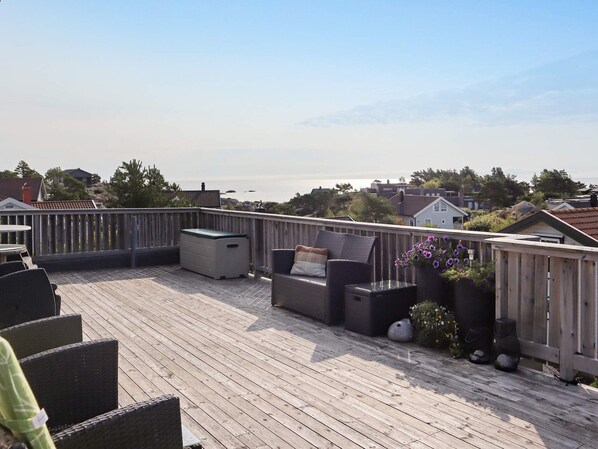 A wooden deck with outdoor furniture, a storage bin, and a flower planter.