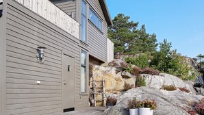 A modern house with a wooden exterior, a garage door, and a large rock formation in the background.