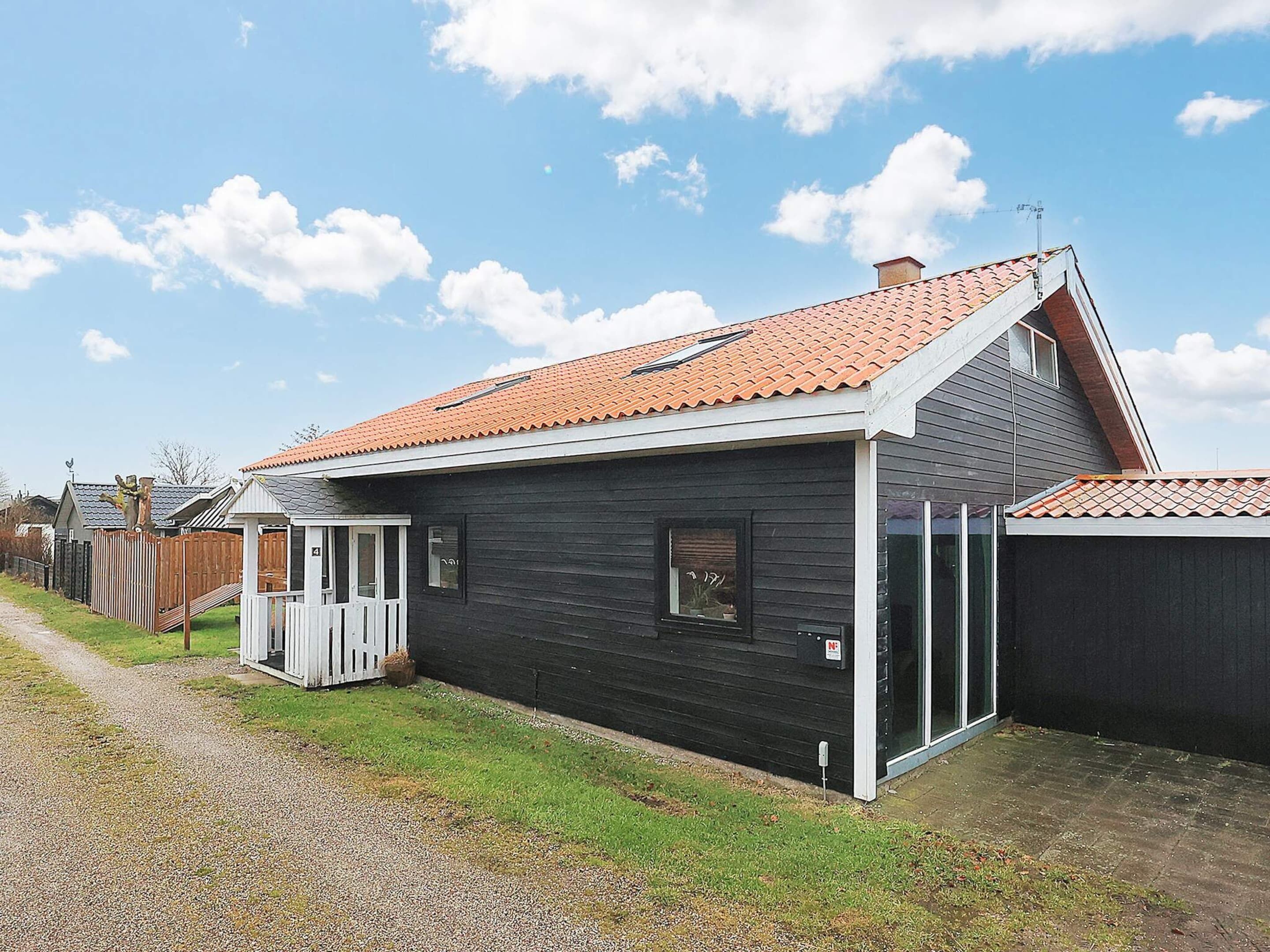 A single-story house with a sloped roof, a small porch, and a fenced yard.