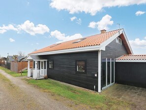 A single-story house with a sloped roof, a small porch, and a fenced yard.