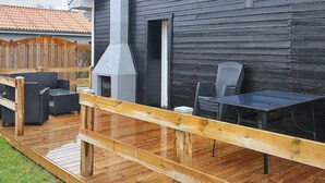 Terassi, jossa on ulkokalusteita, savupiippu ja puinen aita.