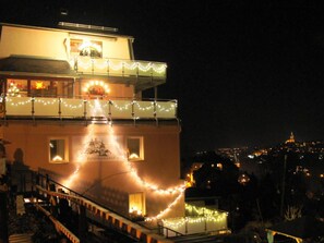 A building with a balcony decorated with string lights, a sign reading "PANORAMABLICK," and a view of a cityscape in the background. - Nice Apartment in the Saarland (Annaberg-Buchholz)
