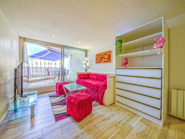 A modern living room with a red sofa, glass coffee table, and a white shelving unit with decorative items.