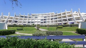 A modern multi-story building with a curved facade, surrounded by well-maintained lawns and hedges. - Le Parador by Interhome (La Grande Motte)