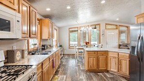 Una cocina con gabinetes de madera, un refrigerador de acero inoxidable, un microondas y una estufa a gas.