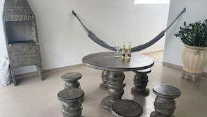 A round table with a stone top, flanked by four stone stools, and two bottles of Corona beer on the table.