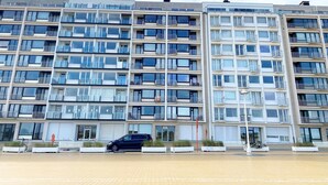 A multi-story residential building with balconies, large windows, and a parking area in front. - Apartment in Nieuwpoort Near the Beach (Nieuwpoort)