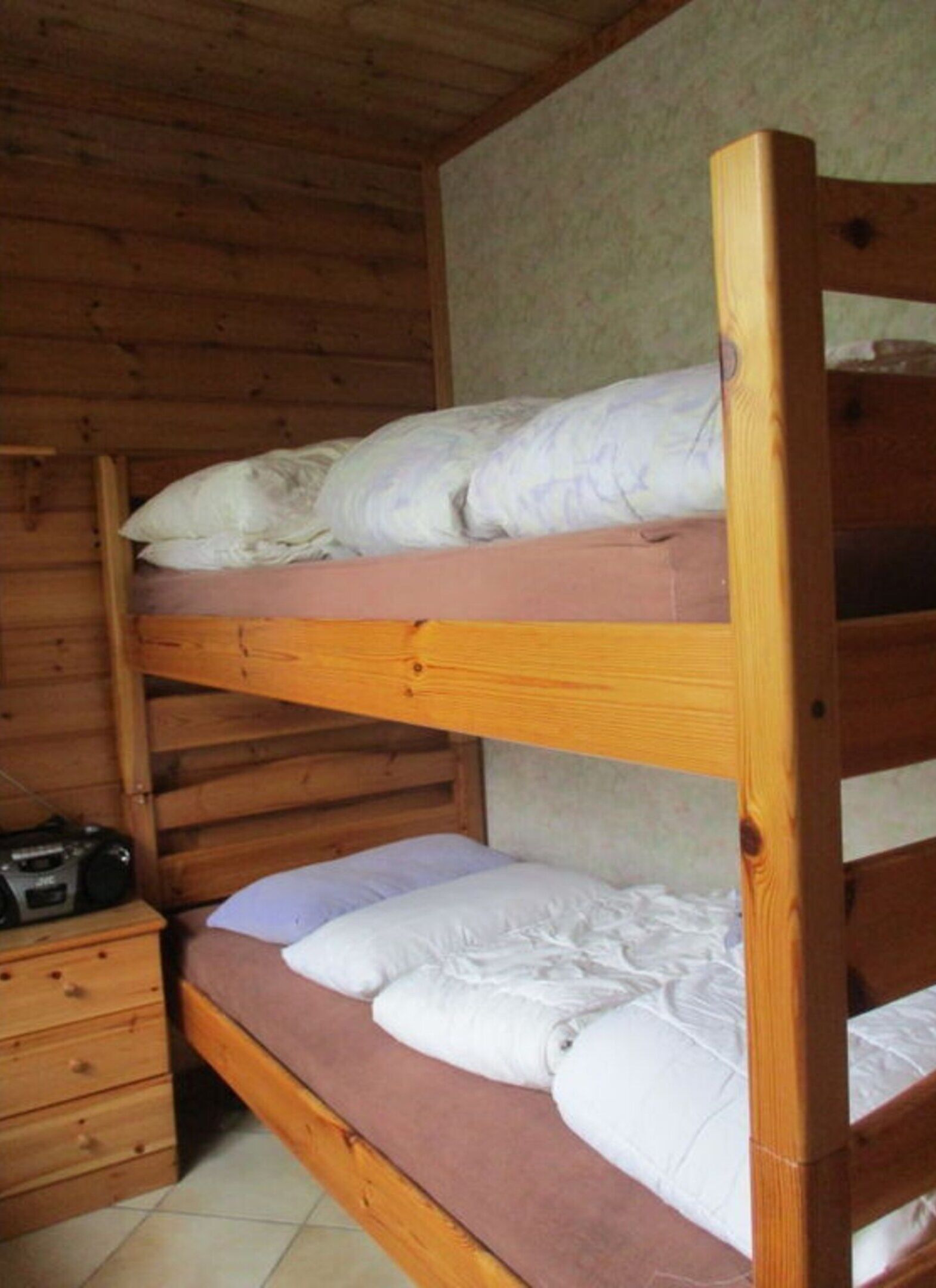 Ein Stockbett mit zwei Etagen, eine hölzerne Kommode und ein Radio.